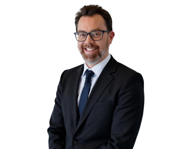 Lindsey Smith wearing a dark suit, white dress shirt, and navy tie, posed against a light blue and white geometric background.