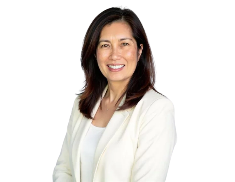 A woman with straight, shoulder-length dark brown hair smiling confidently in a professional headshot. She is wearing a white blazer over a matching top, posed against a plain background.