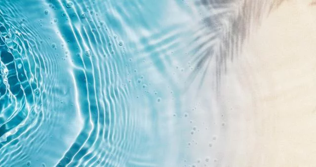 abstract sand beach with palm leaf shadow and blue water wave from above, summer vacation outdoors in tropical paradise nature, background with copy space