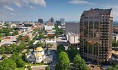 Aerial view of downtown Columbia, South Carolina, with modern office towers and tree-lined streets. The gold-domed building of the St. Peter’s Catholic Church stands out in the foreground.