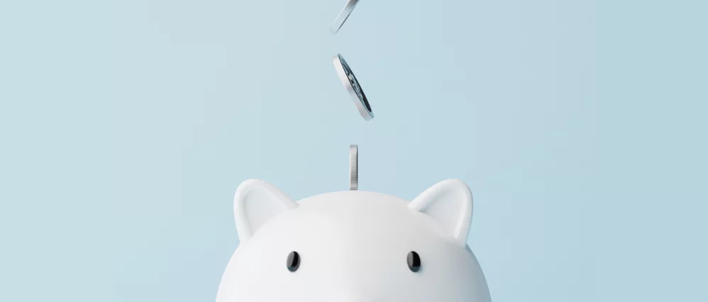 Closeup piggy bank and silver coins falling.