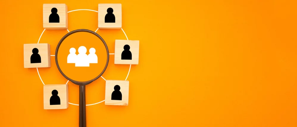 A magnifying glass with people icons isolated on a yellow background.