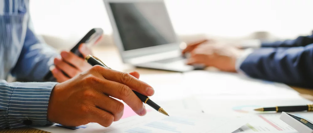 Desk-bound businessman calculates figures, verified accounts, and collaborates in discussions. Proficient in using calculators, aiding each other, and managing annual tax accounts in the audit office