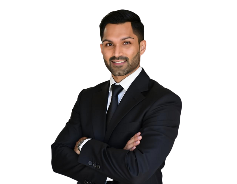 Vikas Bowry dressed in a black suit and tie poses confidently with arms crossed and a friendly smile. The background has been removed, making the image suitable for business profiles or marketing materials.