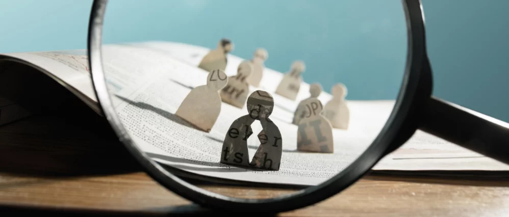 Business recruitment or hiring photo concept. Looking for talent. Icons of candidates are standing on open newspaper under magnifier.