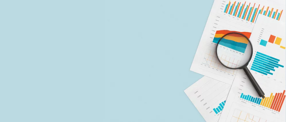 Business graphs, charts and magnifying glass on table.