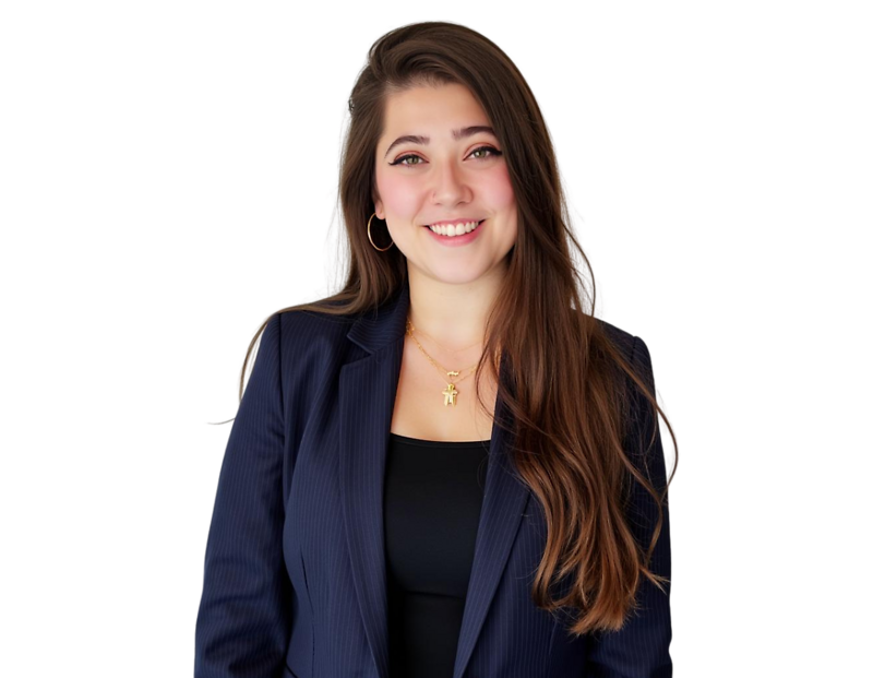 Headshot of a woman with long brown hair, wearing a dark blue pinstripe blazer over a black top. She is smiling and accessorized with gold hoop earrings and two gold necklaces, one featuring an animal-shaped pendant.