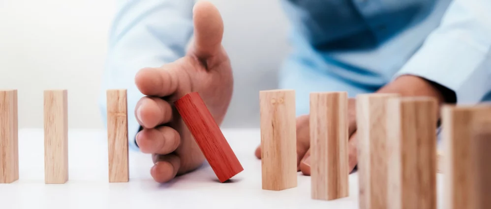 Businessman hand stop dominoes continuous toppled or risk with copyspace. Business risk, strategy and planing concept idea.
