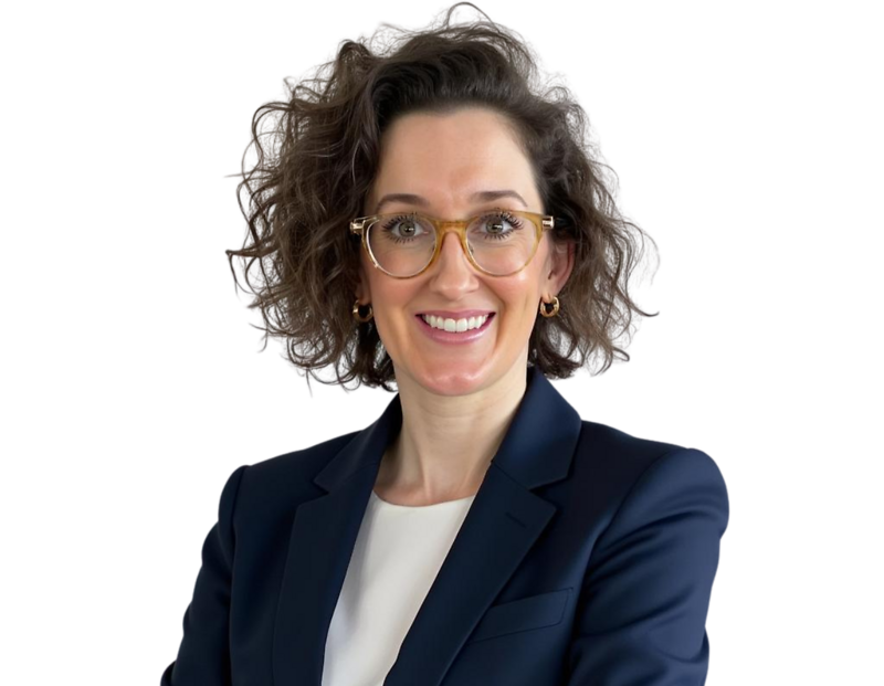 Lindsey Stewart smiling confidently with curly brown hair, wearing clear-framed glasses, gold hoop earrings, and a navy blazer over a white blouse against a plain background.
