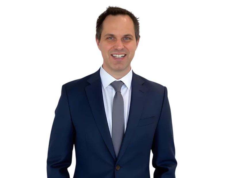 Max Bernas is wearing a navy blue suit, white shirt, and gray tie, posed against a transparent background. His professional attire and approachable expression suggest a business or corporate headshot.