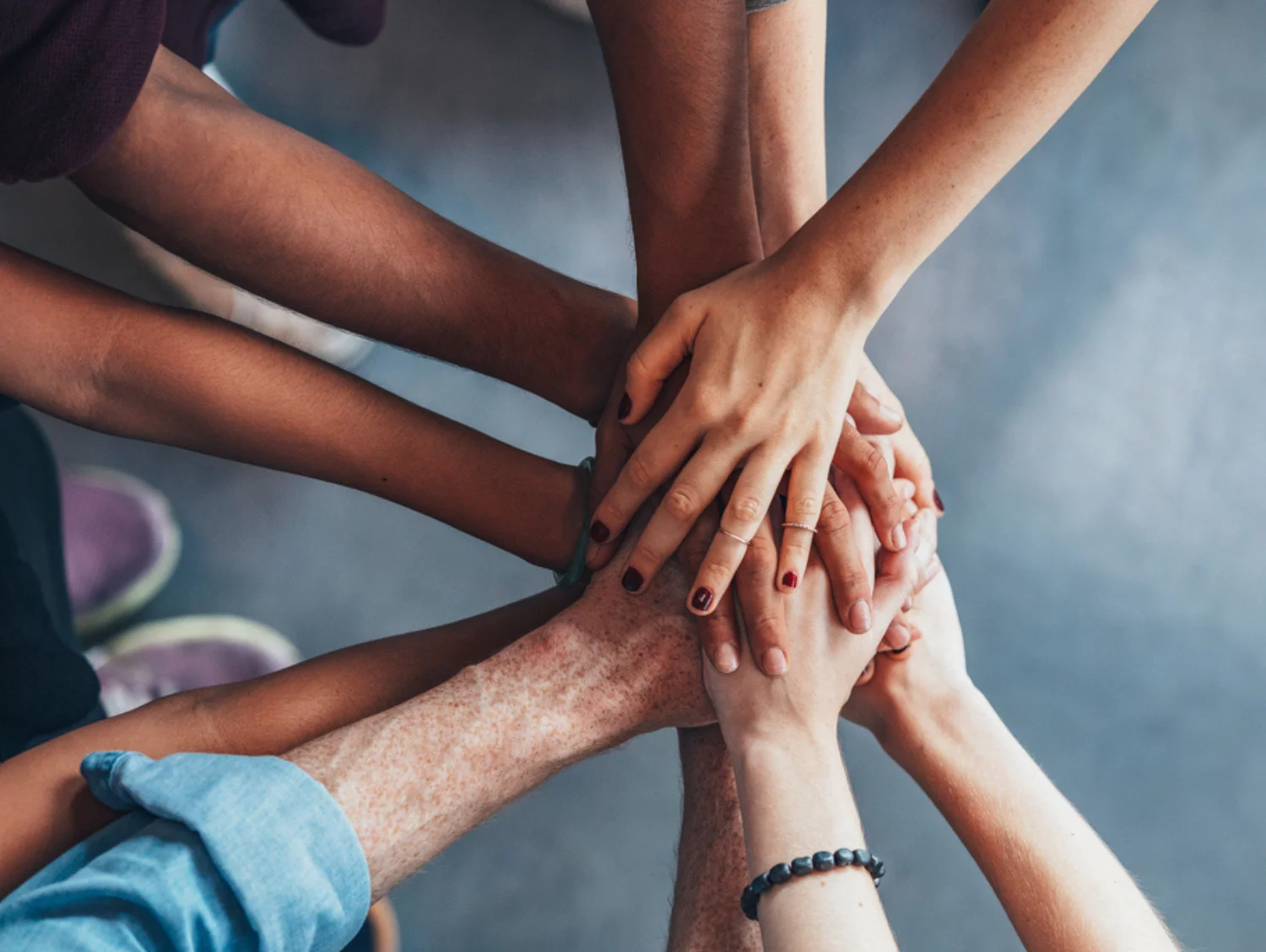 Close up top view of people putting their hands together. Friends with stack of hands showing unity.