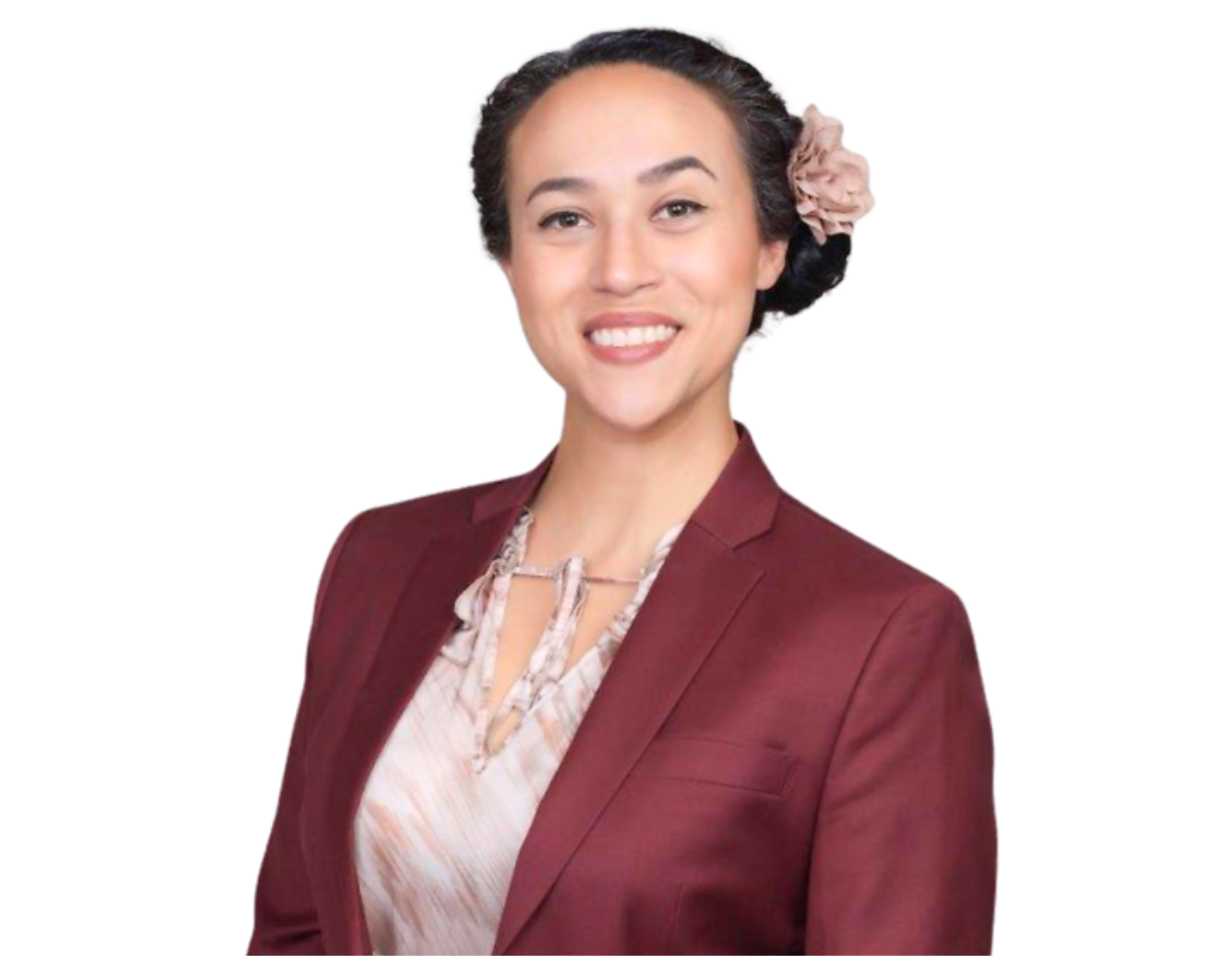 Arcelia Magaña wearing a burgundy blazer over a patterned blouse, with their dark hair styled back and adorned with a light pink flower, posed in front of a blue and white geometric background.