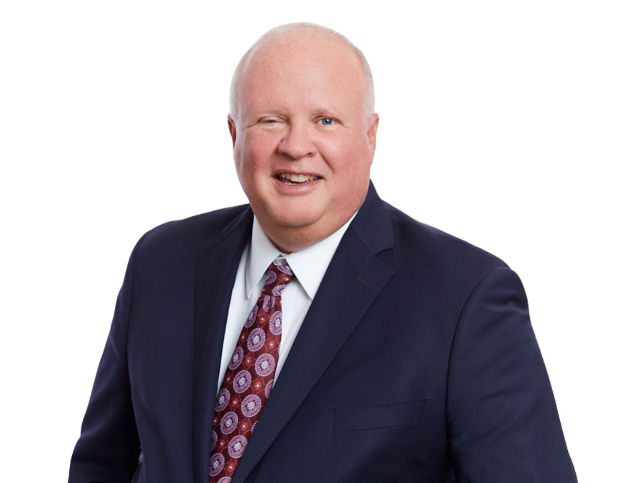 Smiling older man in a dark navy suit with a white shirt and maroon tie featuring a circular pattern, posed against a transparent background. His formal outfit and approachable demeanor suggest a senior professional or executive portrait.