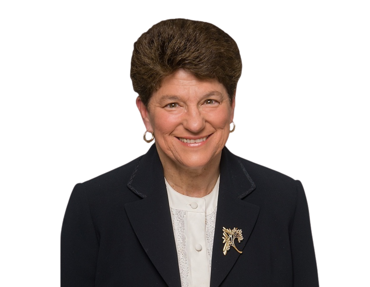 This image shows Ellen Kearns smiling warmly at the camera. She is wearing a navy blazer over a white blouse with lace detail and a decorative gold brooch shaped like a flower or branch. The background has been remove