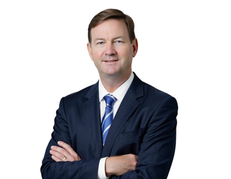 Hunter Johnson in a dark suit with a blue and white striped tie stands with arms crossed, smiling against a light blue and white geometric background.