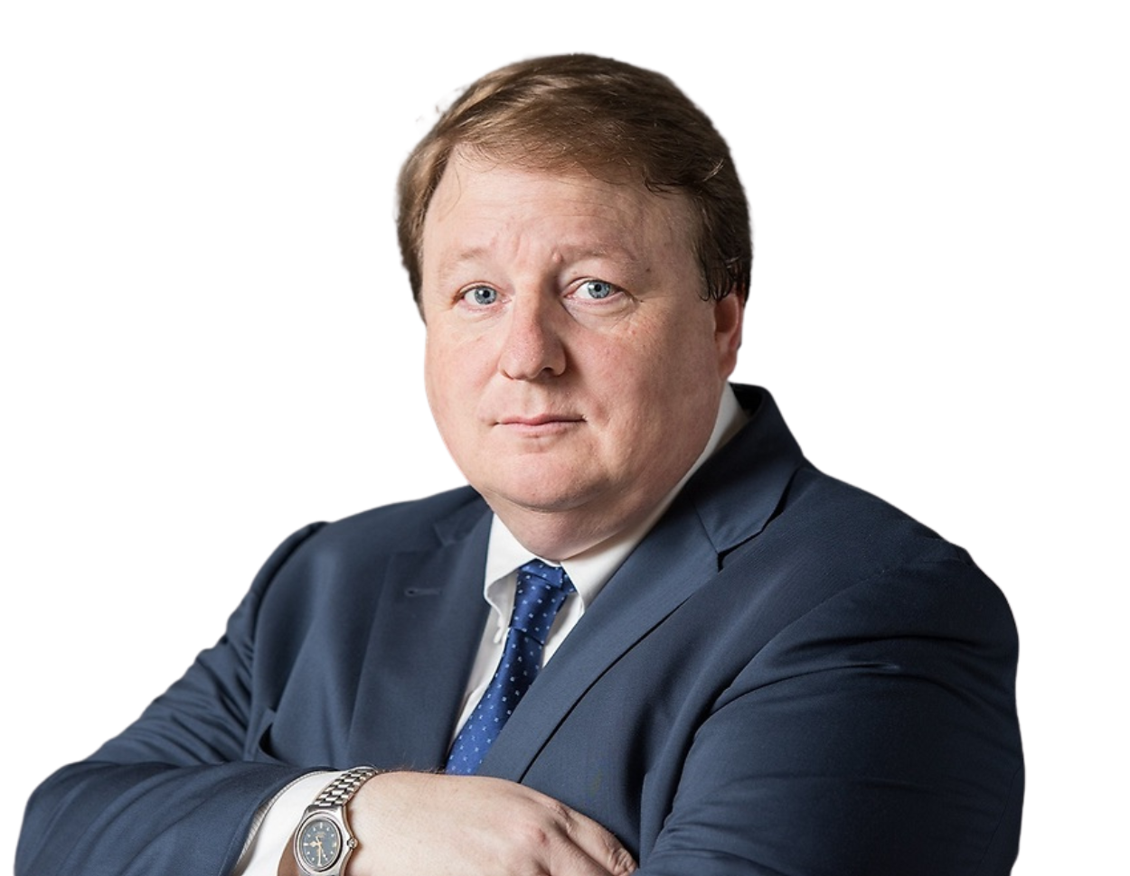 Photo of Damon Kitchen wearing a navy blue suit, white shirt, and blue patterned tie, with a watch on his wrist, against a plain background.