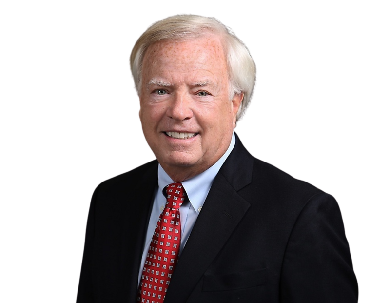Pat Tyson wearing a dark suit, light blue shirt, and red patterned tie against a plain background.