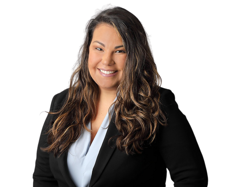 Professional headshot of Amanda Morejon smiling, wearing a light blue blouse under a black blazer, with long wavy hair, posed against a softly blurred light background.
