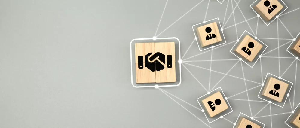 Hand shake icon on wooden cube block which connection with human icon for business deal and agreement concept.