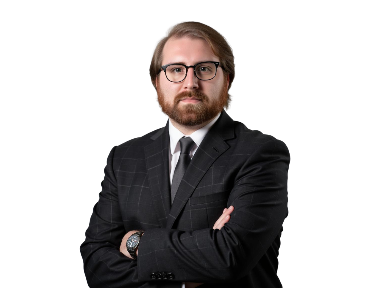 Man with a serious expression wearing a dark plaid suit, black tie, and glasses, standing with arms crossed against a transparent background. His light brown hair is neatly combed back and he has a full beard.