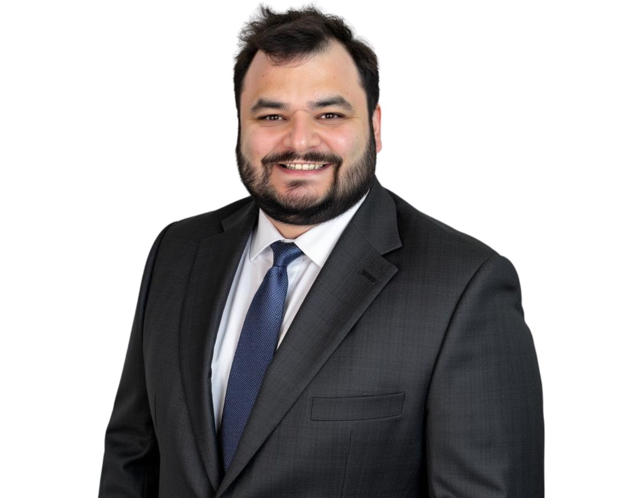 Ethan Schutzman wears a dark suit, white shirt, and blue tie, smiling against a light blue and white geometric background.