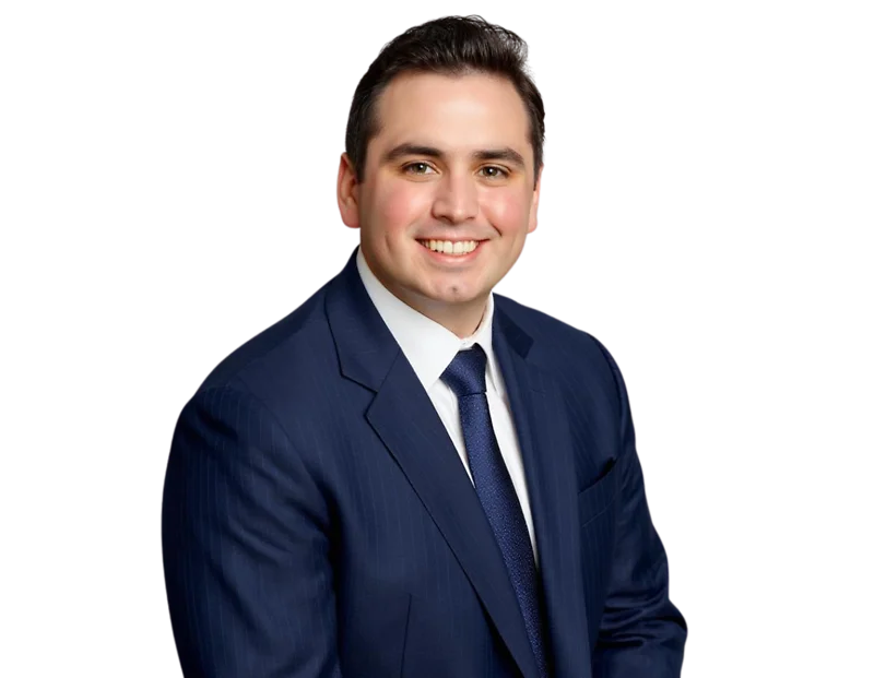 Smiling professional man with short dark hair wearing a navy blue suit, white dress shirt, and textured blue tie, posed against a transparent background. His polished appearance and friendly expression make the image suitable for a corporate or executive