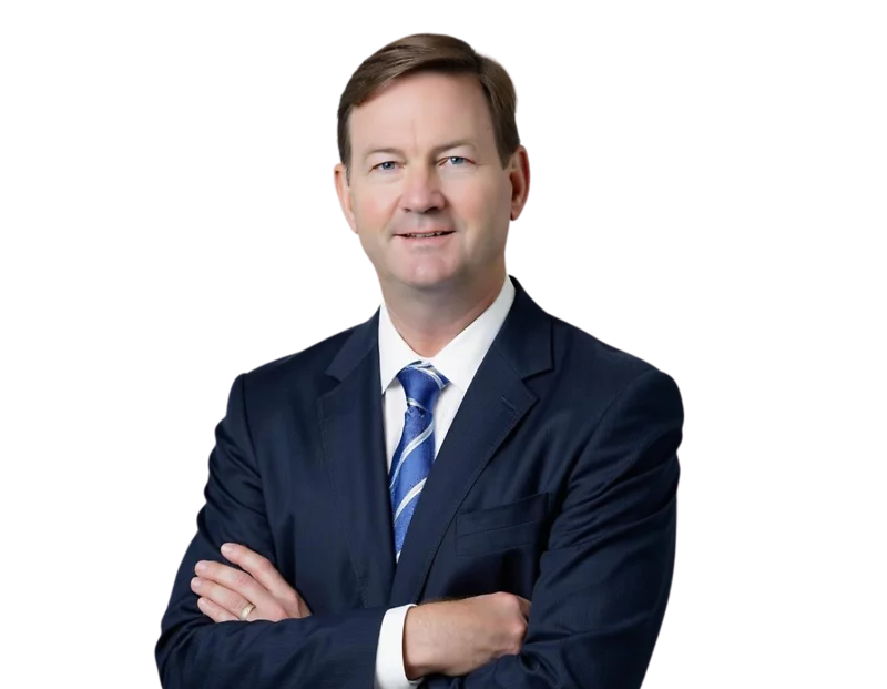 Hunter Johnson in a dark suit with a blue and white striped tie stands with arms crossed, smiling against a light blue and white geometric background.