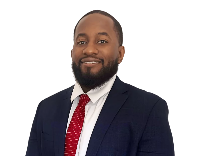 Smiling man with a short beard wearing a dark navy suit, white dress shirt, and red tie with small white dots, posing against a transparent background. He presents a polished and approachable business professional look.