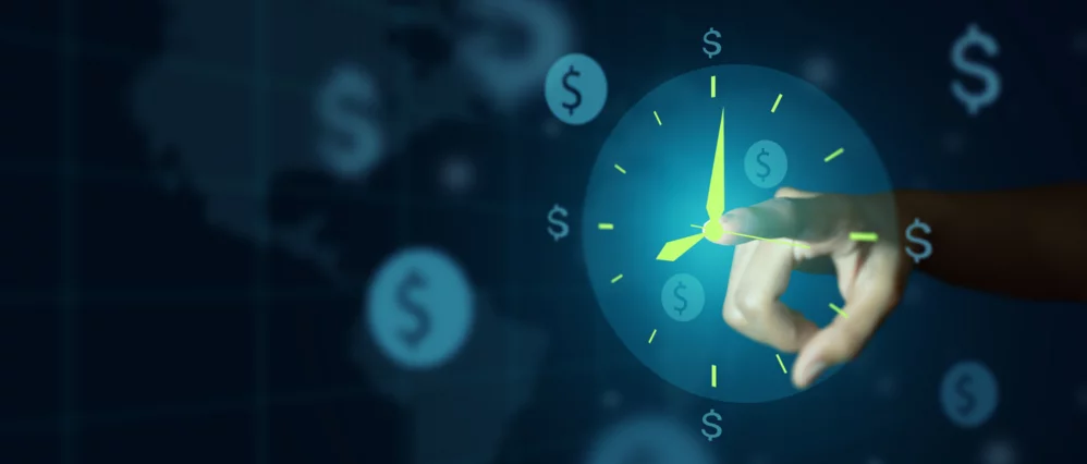 Close up of a hand interacting with a glowing digital clock interface surrounded by floating dollar symbols on a dark blue background. The illuminated clock face emphasizes time while the currency icons reinforce financial value.