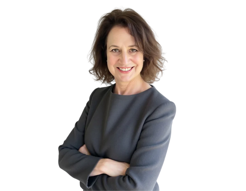 A professional portrait of a woman with shoulder-length brown hair styled in soft waves. She is smiling directly at the camera and wearing a long-sleeved dark gray dress. Her arms are crossed in a confident, approachable pose.