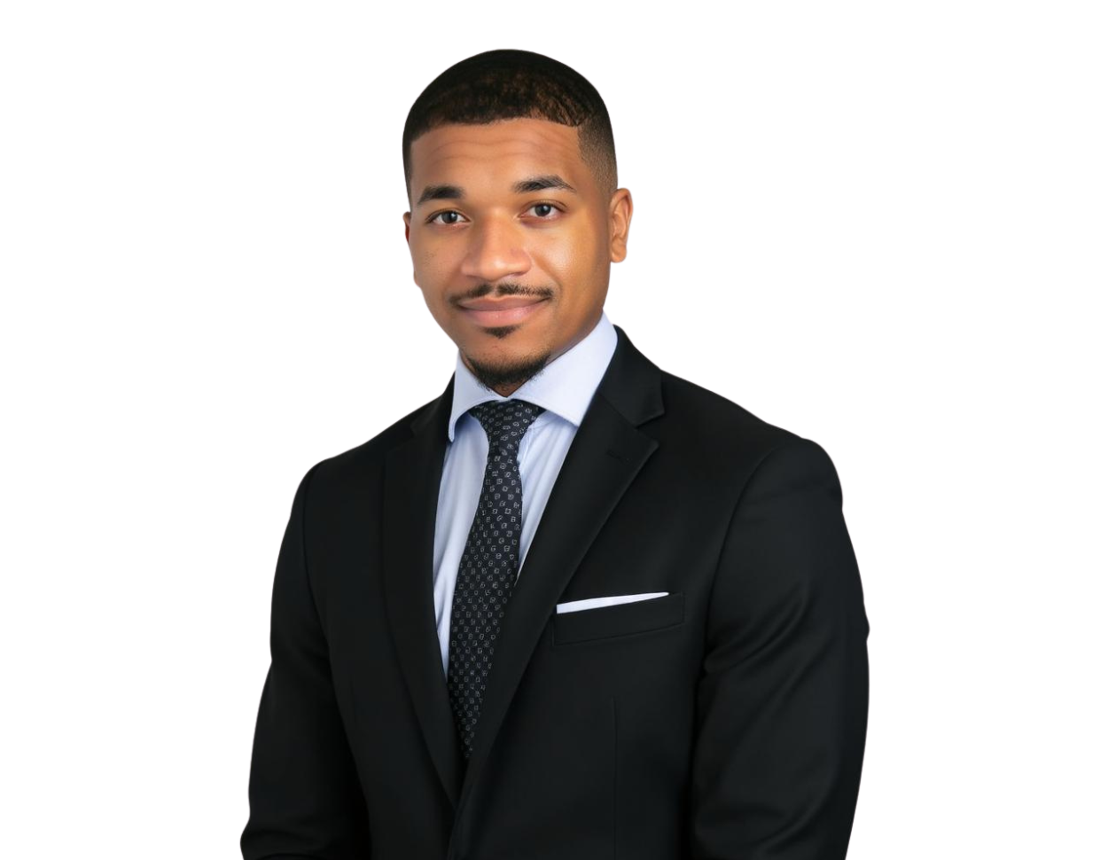 Professional headshot of a young man in a black suit with a white shirt and dark patterned tie, standing against a white background and smiling slightly. His look is polished and business-ready, with neatly groomed hair and a confident posture.