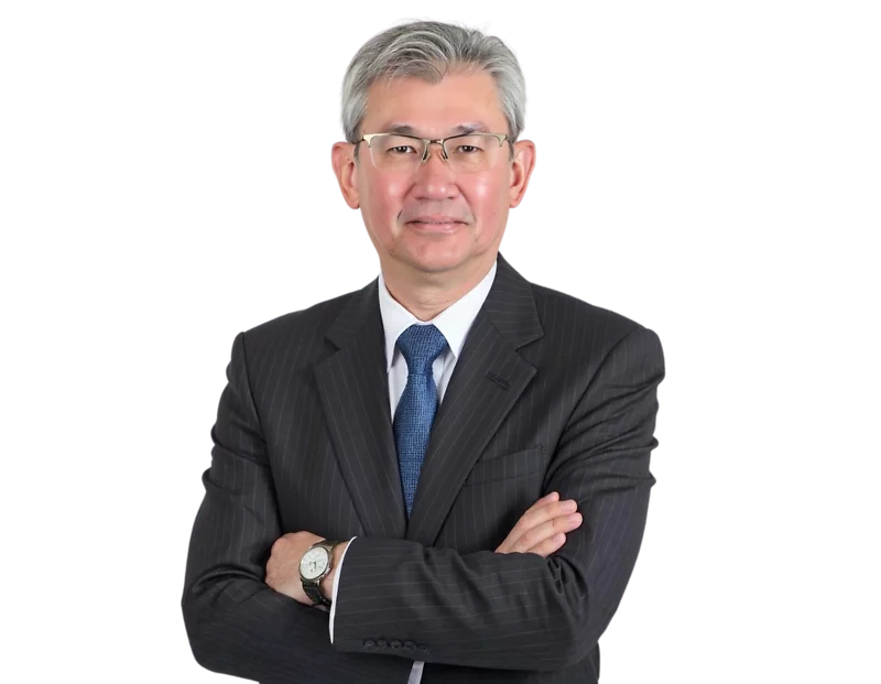 Jim Goh poses confidently with arms crossed in a professional headshot. He is wearing a dark pinstripe suit, white shirt, blue tie, and a wristwatch, against a plain background.