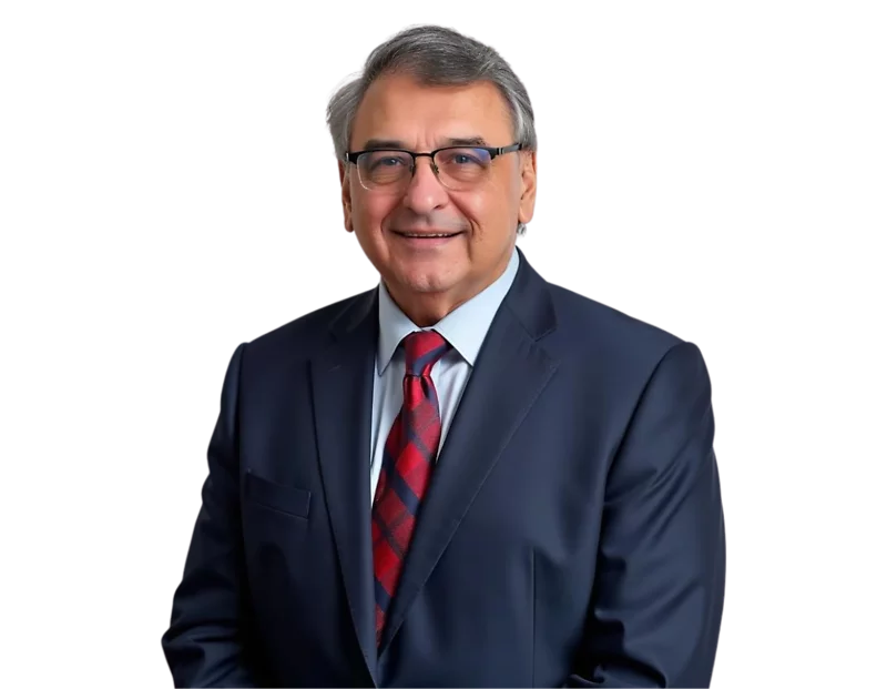 Nestor Barrero in a navy blue suit and red patterned tie, smiling warmly while wearing glasses, posed against a transparent background. His formal attire and professional demeanor suggest a corporate or leadership role.