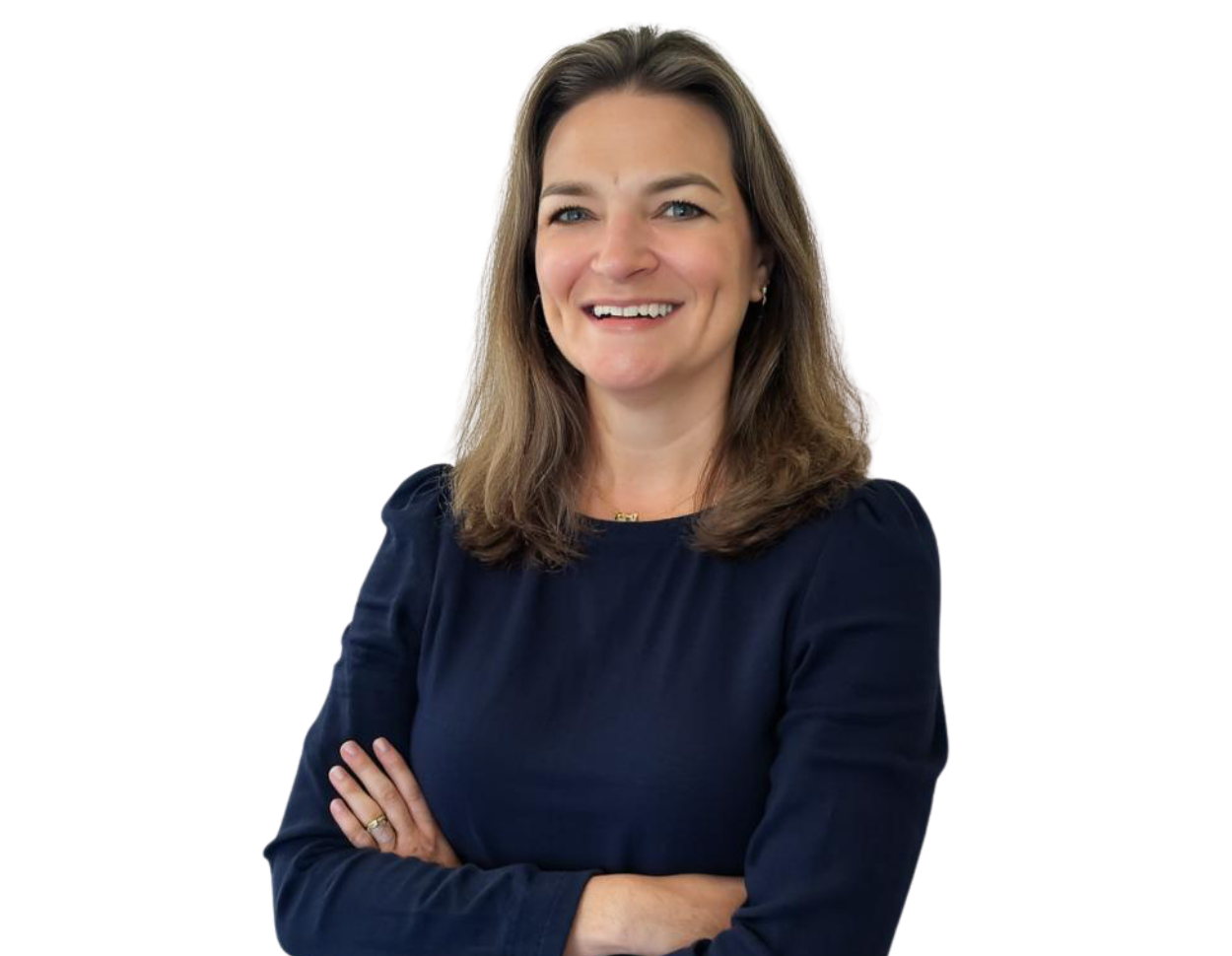 Professional head-and-torso portrait of Missy Spainhour, smiling with her arms crossed. She is wearing a dark long-sleeved top and standing against a light, modern background with soft blue geometric accents.
