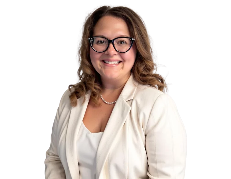 Headshot of Nicole Davies wearing black glasses, a white blazer, and a pearl necklace, posed in front of a light blue and white geometric background.