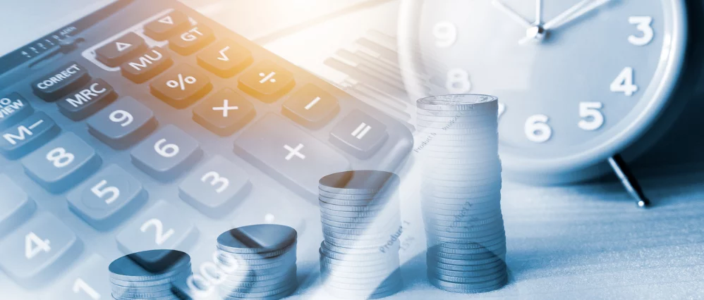 Double exposure image combining a close up of a calculator keypad with stacks of coins arranged in increasing height and a large clock face in the background. The layered composition uses cool blue tones with a warm light flare, emphasizing time, money, a