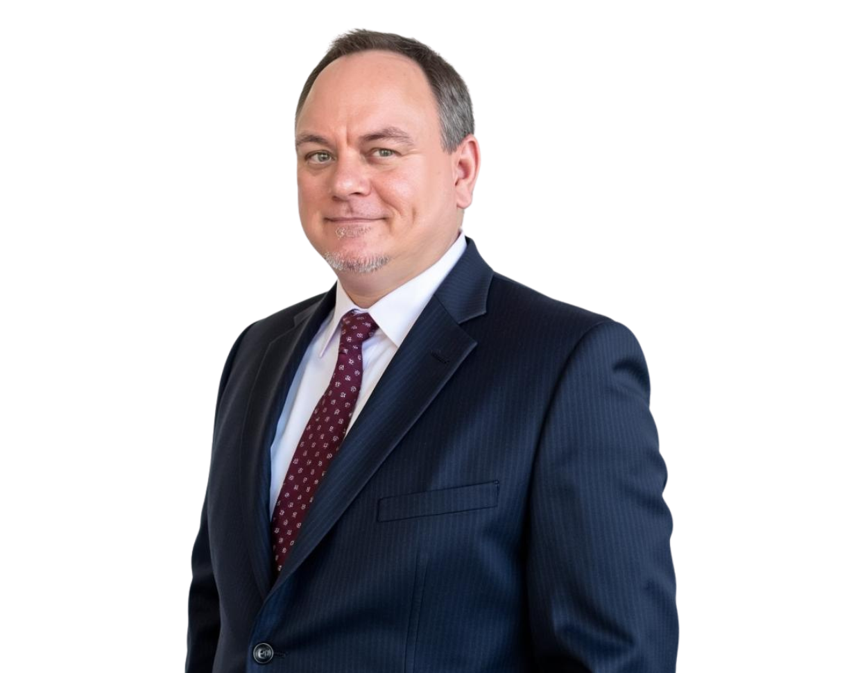 Jack Wallace stands in a dark pinstripe suit and maroon patterned tie, smiling slightly with a confident and approachable demeanor. He has short-cropped hair and a neatly groomed goatee, dressed professionally against a plain background.
