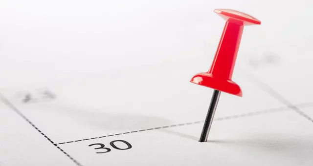 Close-up of calendar with a red pin on a specific date