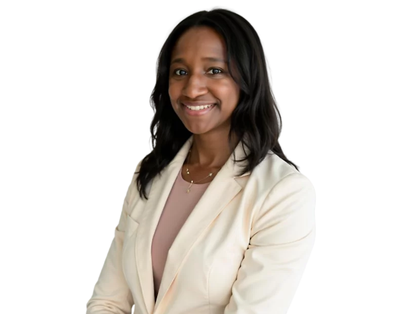 Professional headshot of Ashley Waring smiling, wearing a light beige blazer over a soft pink top, with shoulder-length dark hair, posed against a softly blurred light background.
