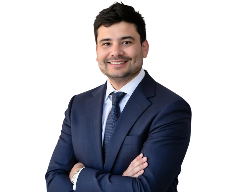 A photo of Rodrigo Pocasangre smiles confidently while wearing a dark blue checkered suit, white shirt, and navy tie. He stands against a transparent background with his arms crossed, exuding professionalism and approachability.