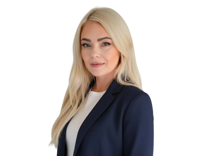A professional portrait of a woman with long, straight blonde hair wearing a navy blazer over a white blouse. She is turned slightly toward the camera with a calm, confident expression and a slight smile. The image is cropped from the waist up, with no vi
