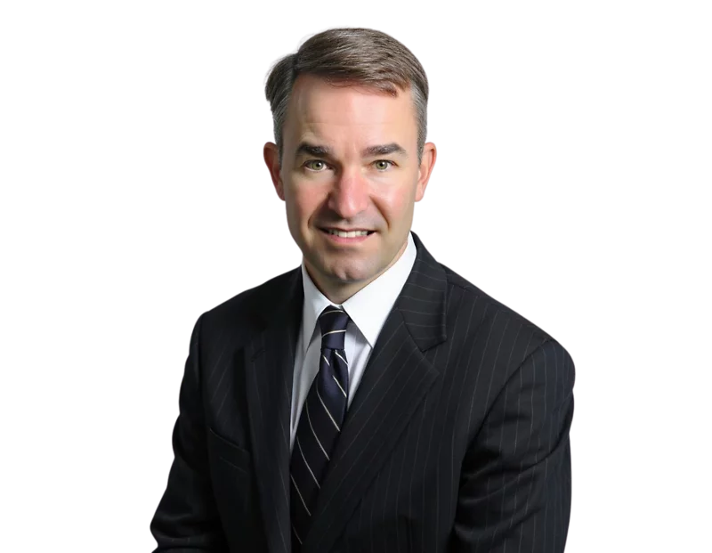 Jonathan Martin, wearing a dark pinstripe suit and striped tie, poses against a black background with a slight smile. His short brown hair is neatly combed to the side.