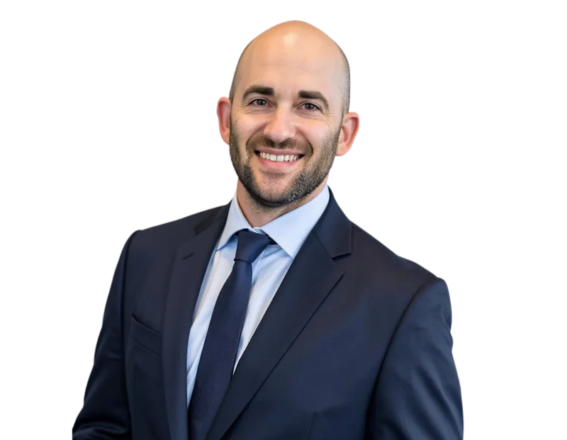 Jeffrey Fields in a dark suit and blue tie smiles while standing against a light blue and white geometric background.