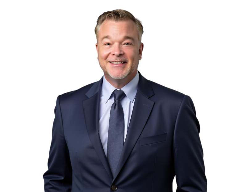 Jason Cherry in a dark navy suit and tie smiles while standing against a light blue and white geometric background.