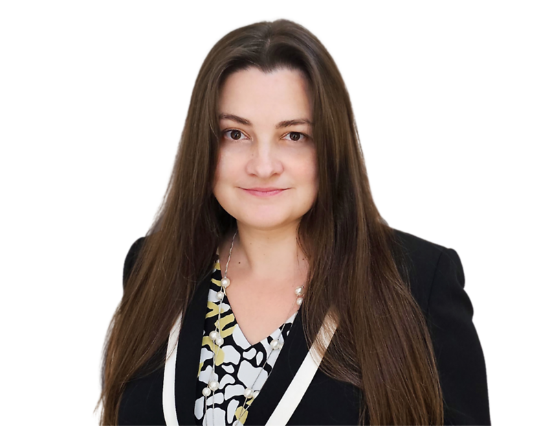 Rebecca Eng, smiling, wearing a black blazer over a patterned blouse with pearl accents against a plain background.