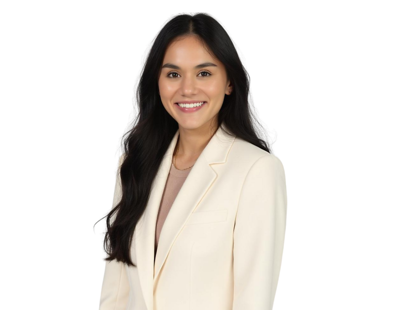 Smiling woman with long dark hair wearing a cream-colored blazer over a beige top. She is facing forward against a transparent background.