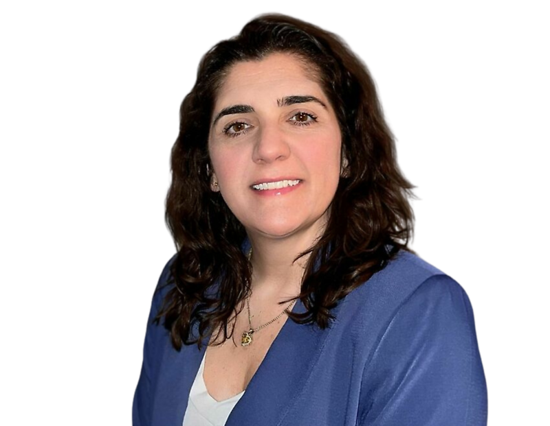 Julie Hess, smiling, wearing a blue blazer over a white top and a delicate necklace, against a plain background.