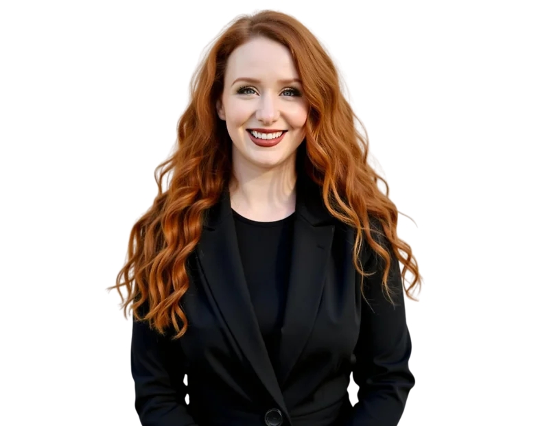 Smiling professional woman with long, voluminous red hair wearing a black blazer over a black top, facing the camera against a transparent background. Her bright expression and polished appearance convey confidence and a strong, approachable presence in a