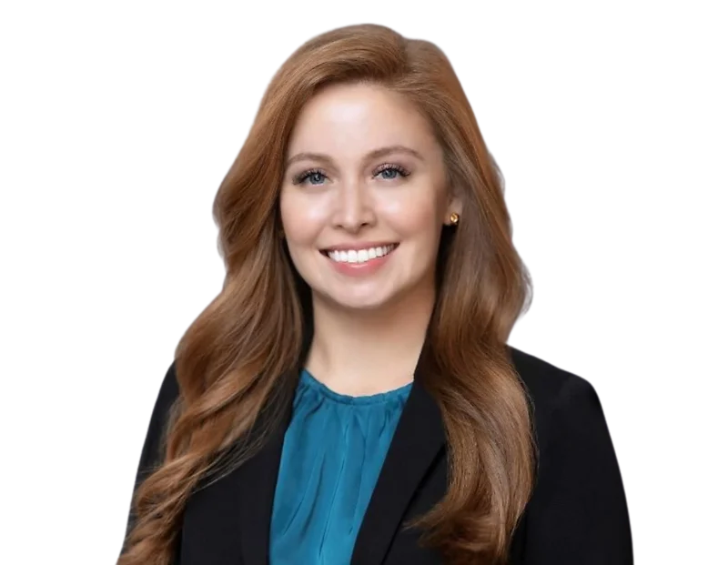 Smiling professional woman with long, wavy auburn hair wearing a black blazer over a teal blouse, posing against a transparent background. She has a friendly, polished appearance suited for business or corporate settings.