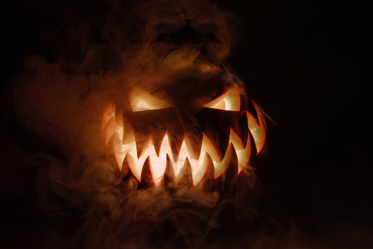 Spooky Halloween Jack O Lantern A glowing orange Halloween jack o lantern with sharp triangular eyes and a wide menacing grin filled with jagged teeth. Thick swirling smoke surrounds the carved pumpkin against a pitch black background, creating a spooky atmosphere.